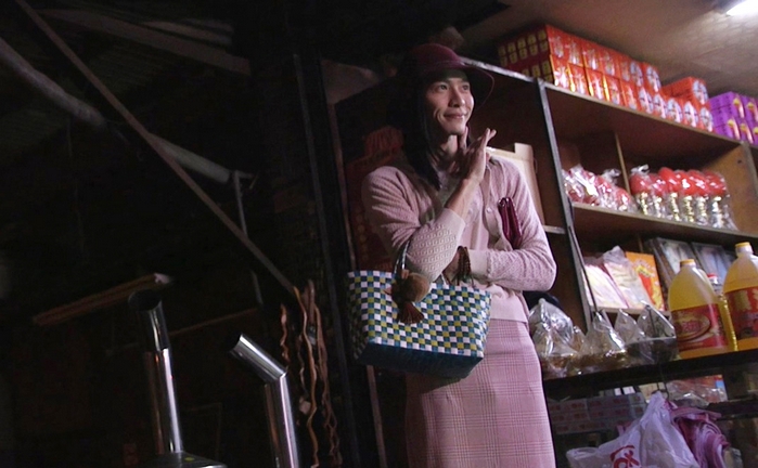 田士廣從頭到腳的帽子、薄外套與裙子皆穿著紫藕色，躲在雜貨店角落