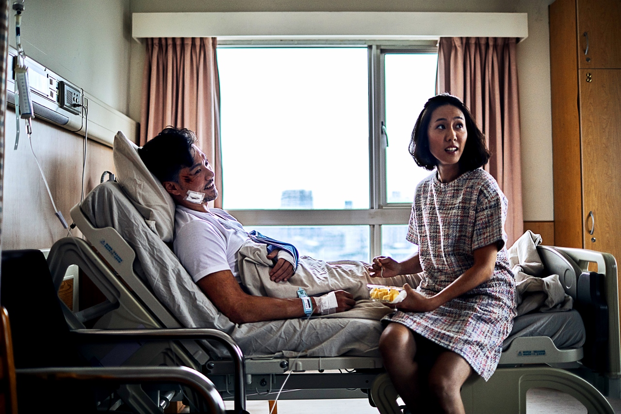 《我的靈魂是愛做的》劇照：張晉豪躺於醫院病床，他的妻子側坐在床上，兩人笑著看著鏡頭外的斜上方